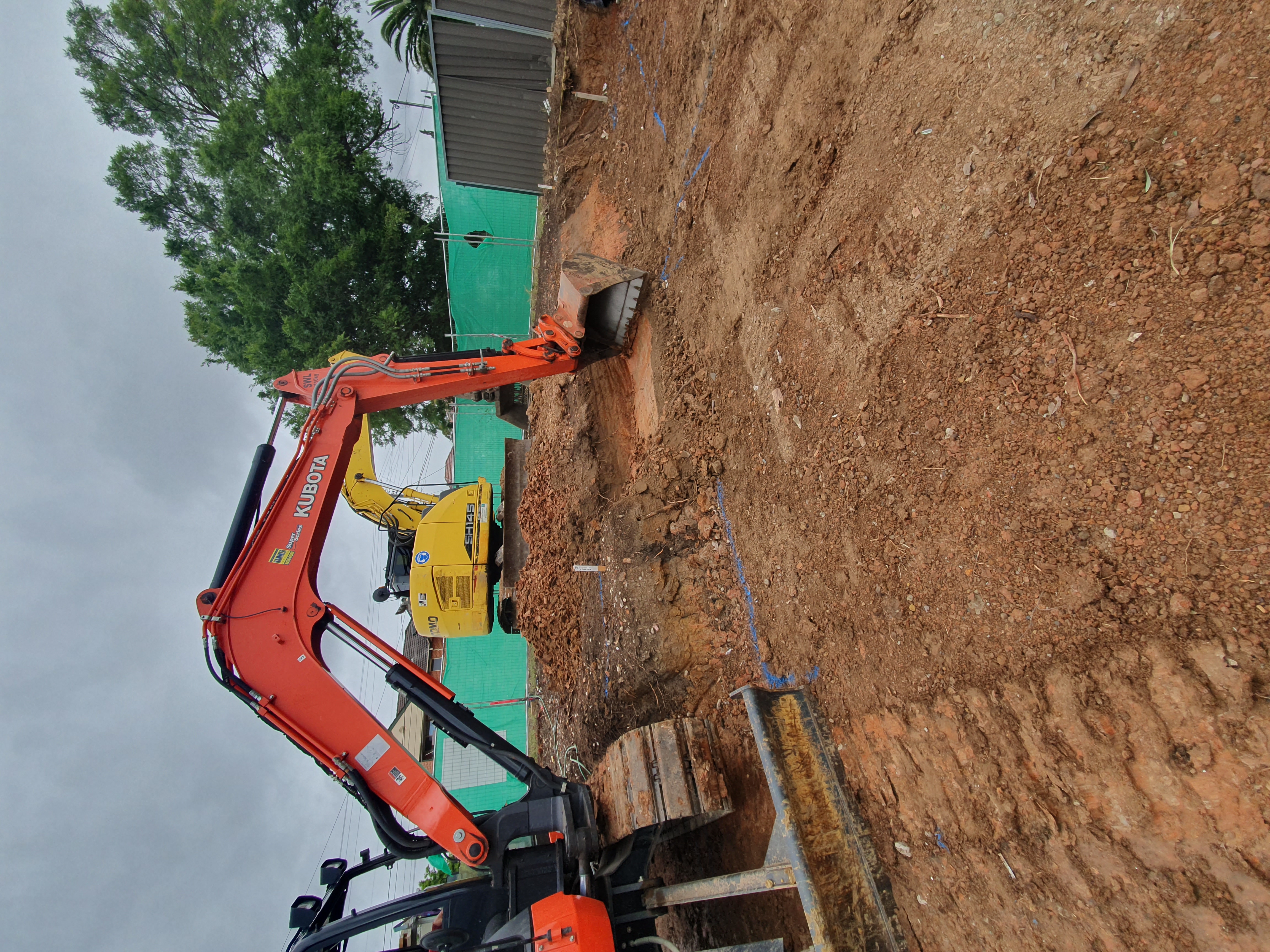 An image of 2 excavators working clearing a site in preparation to lay down a foundation slab, a Diligent Concrete Group project